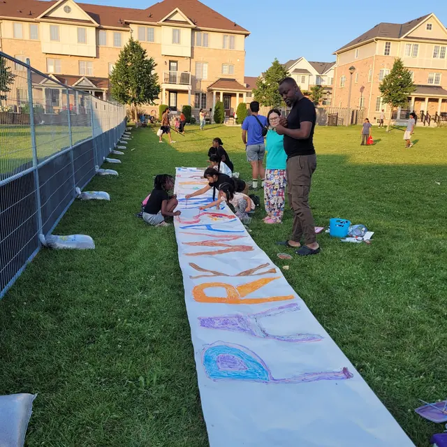 The banner takes shape against the fence line.